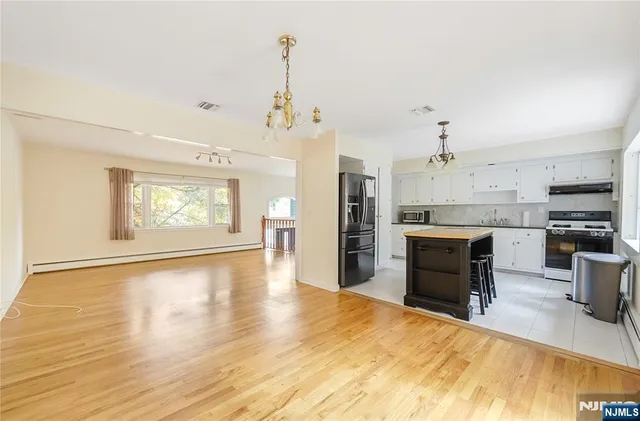 a large kitchen with stainless steel appliances kitchen island granite countertop a refrigerator a stove a sink dishwasher with a dining table and chairs with wooden floor