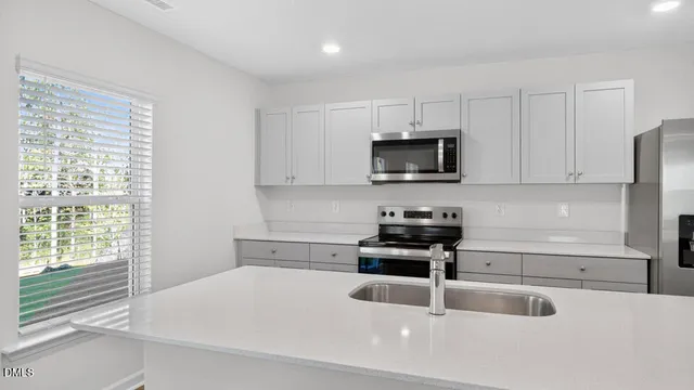 a kitchen with granite countertop a stove a sink and a microwave