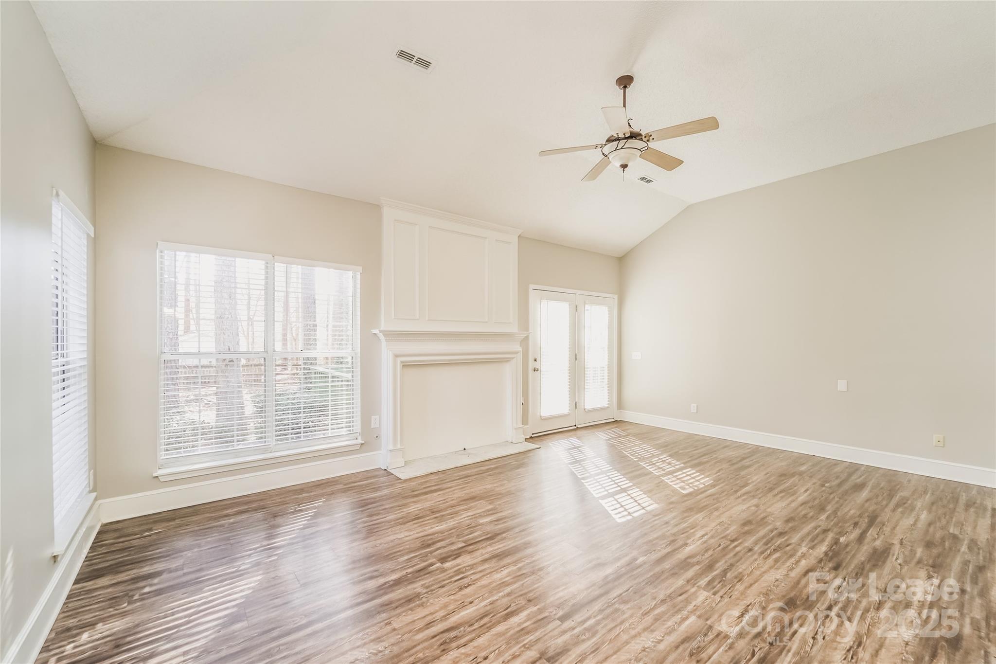 7121 Scuppernong Court Charlotte, NC 28215 - Photo 4 of 15 an empty room with wooden floor ceiling fan and windows