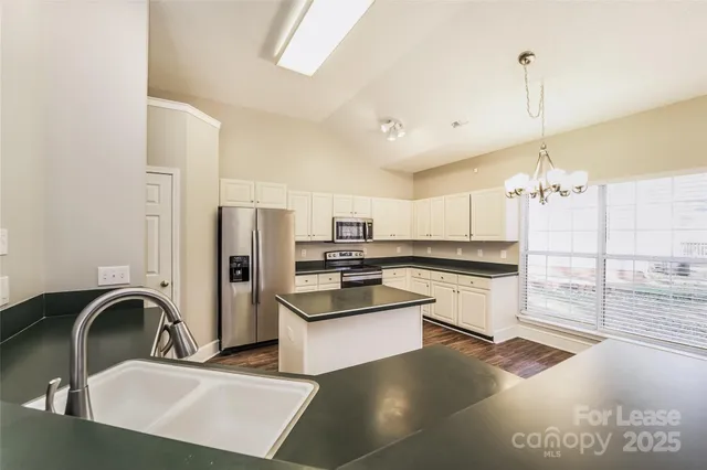 a kitchen with stainless steel appliances granite countertop a sink a stove and refrigerator