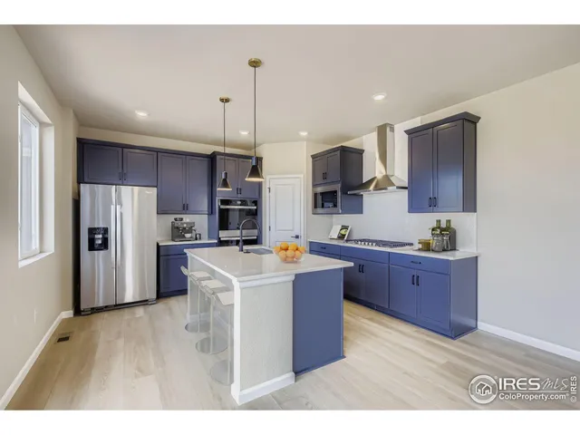 a kitchen with stainless steel appliances kitchen island granite countertop a refrigerator a sink dishwasher a stove and a refrigerator