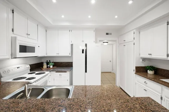 a patio with table and chairs with potted plants and wooden fence