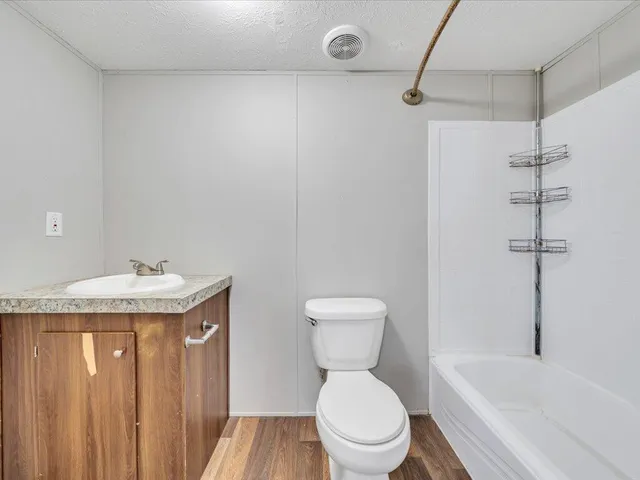 a bathroom with a granite countertop sink a toilet and bathtub