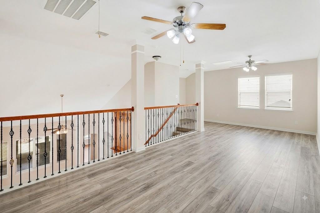 4908 Rushden Road McKinney, TX 75070 - Photo 30 of 34 Expansive open loft area featuring wood-finish flooring, two ceiling fans with lighting, and multiple windows