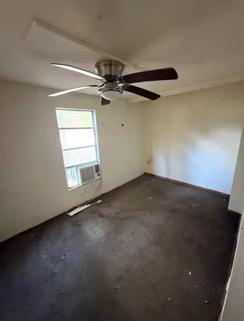 an empty room with windows and fan