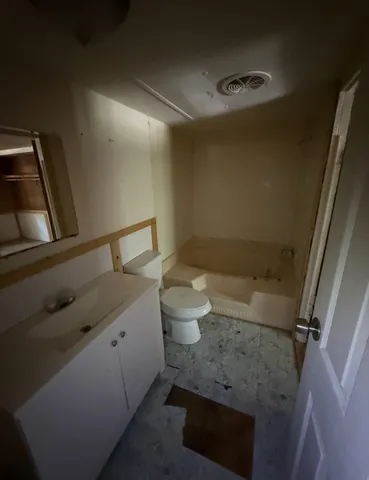 a bathroom with a granite countertop sink toilet and a mirror