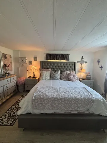 a bedroom with a large bed and wooden floor