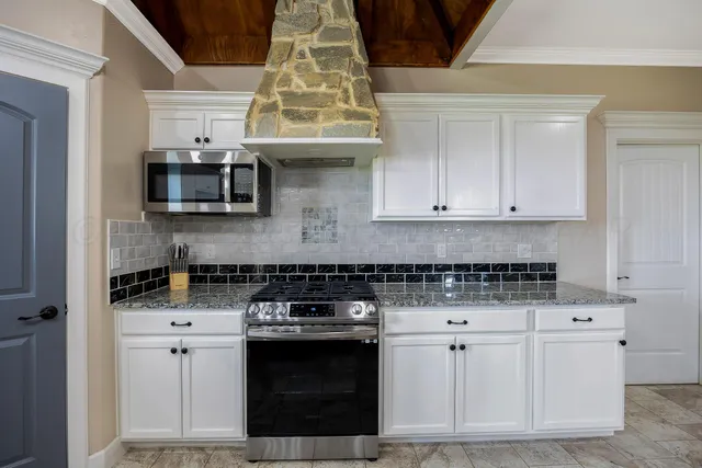 a kitchen with stainless steel appliances granite countertop a stove and a white cabinets
