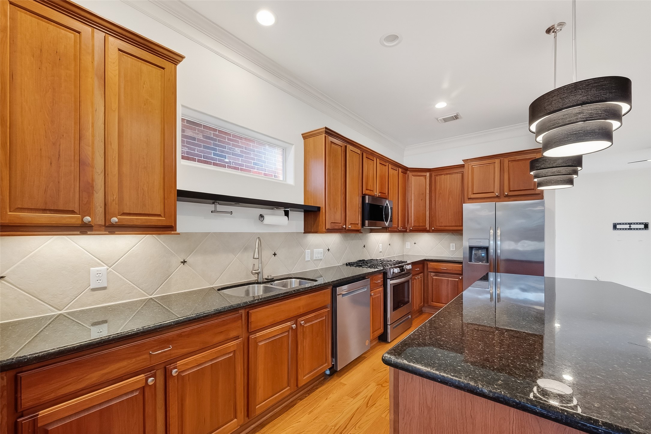 1004 Stanford Street, Unit A Houston, TX 77019 - Photo 13 of 38 Generous granite countertop space and natural wood cabinetry flows into the bright kitchen