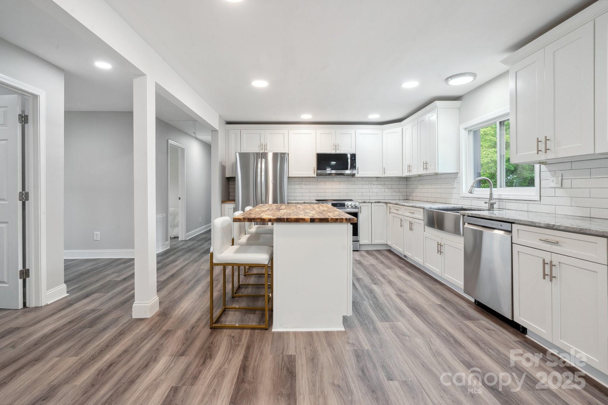 554 Isle Of Pines Road Mooresville, NC 28117 - Photo 12 of 44 a kitchen with wooden floors white cabinets and stainless steel appliances
