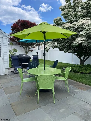 a view of a table and chairs under an umbrella in backyard