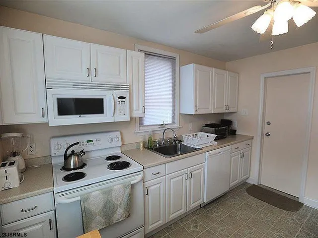 a kitchen with white cabinets and white appliances
