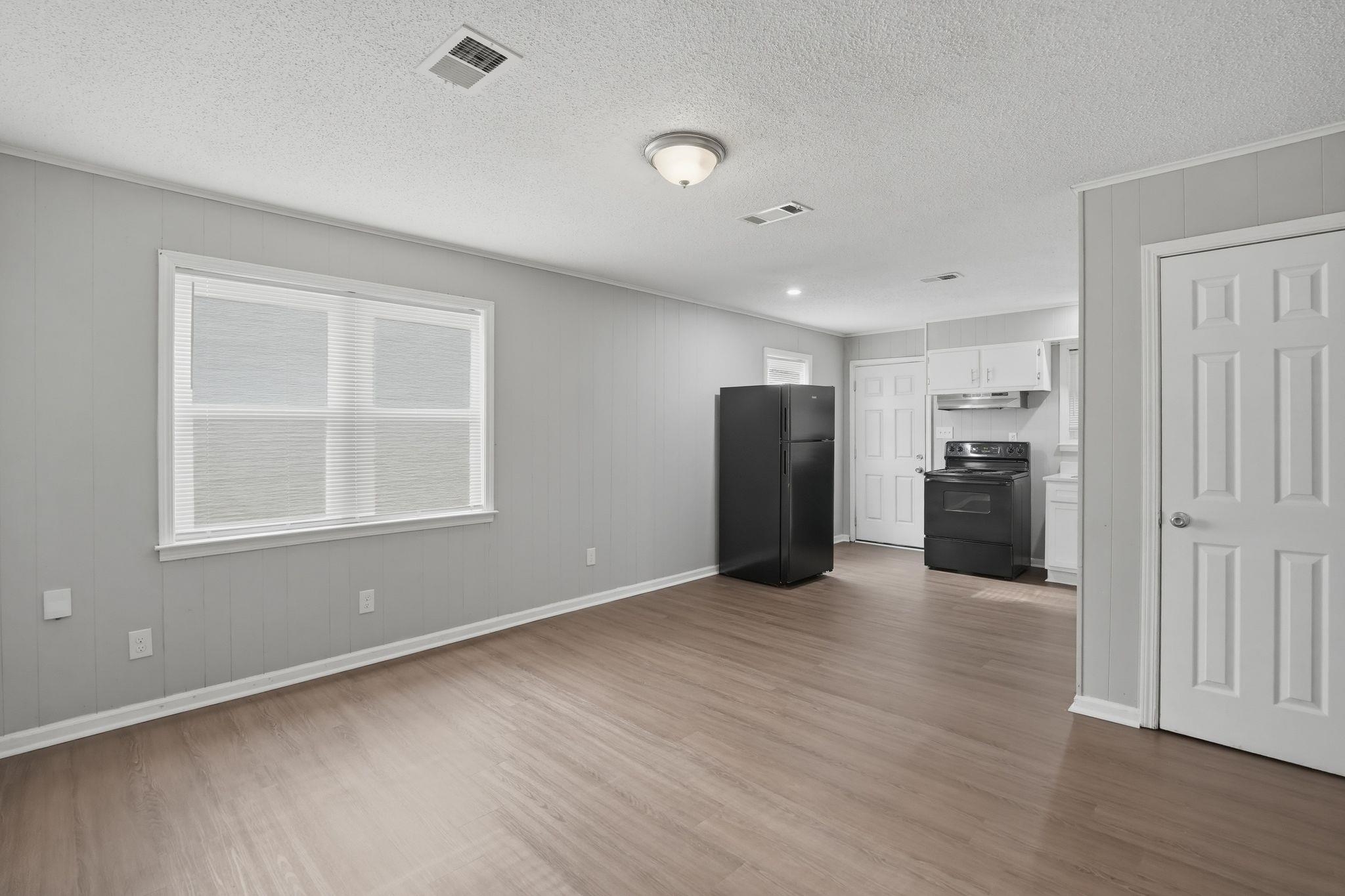 4686 Gill Road Memphis, TN 38109 - Photo 16 of 32 Open-concept living space with wood-finish flooring, light grey paneling, and a contemporary kitchen