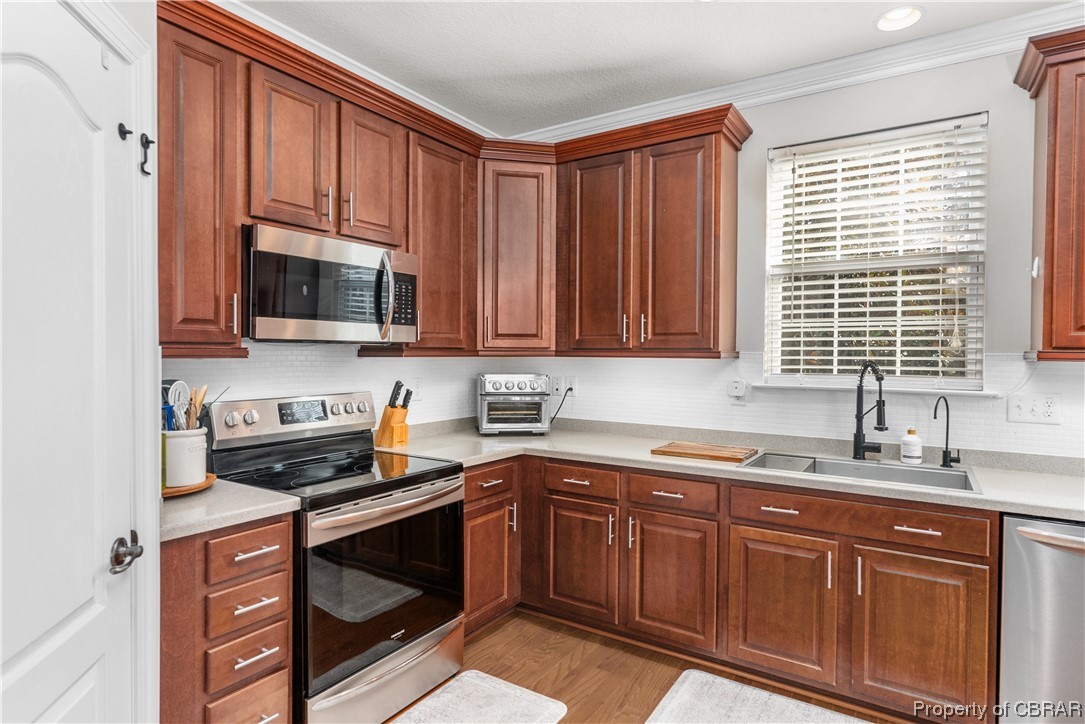 2124 Piedmont Road Suffolk, VA 23435 - Photo 20 of 41 Kitchen featuring stainless steel appliances, ornamental molding, light hardwood / wood-style flooring, and sink