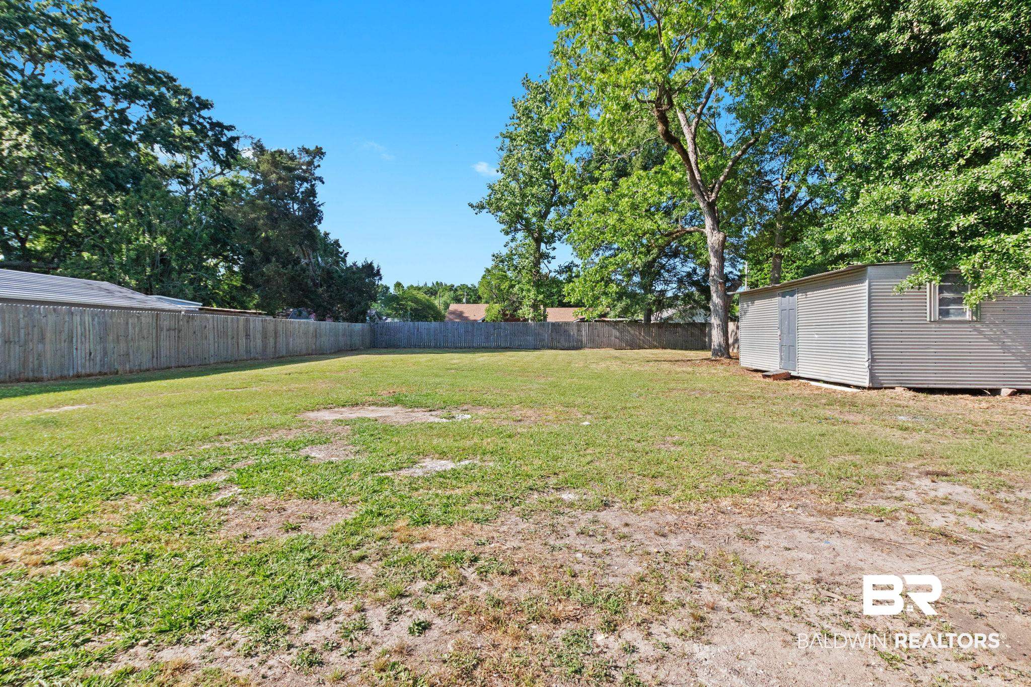 311 Cloverdale Road Atmore, AL 36502 - Photo 57 of 63 Expansive outdoor space featuring a wood fence, mature perimeter trees, and a detached storage shed