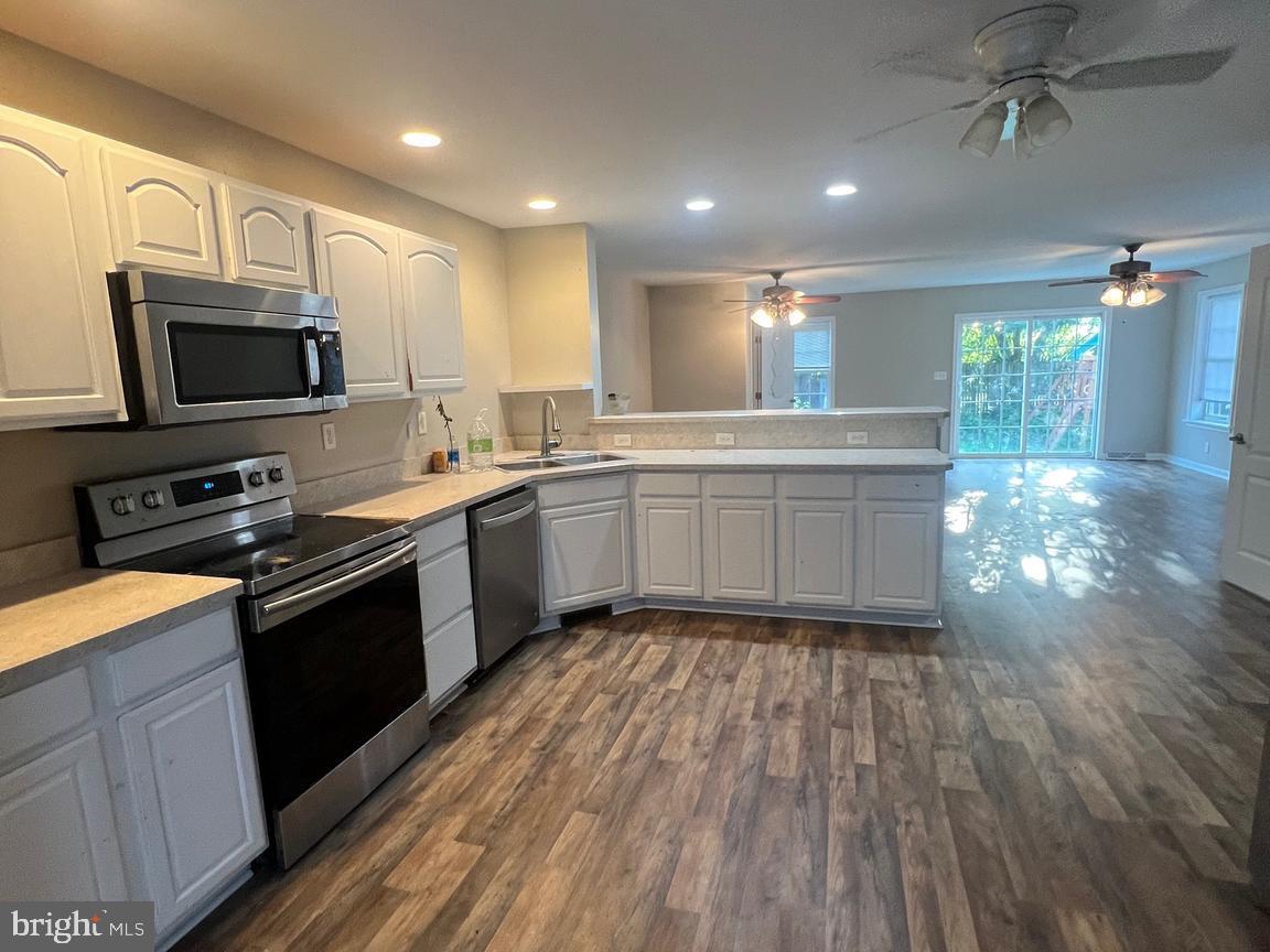 a kitchen with stainless steel appliances granite countertop hardwood floor sink stove dining table and chairs