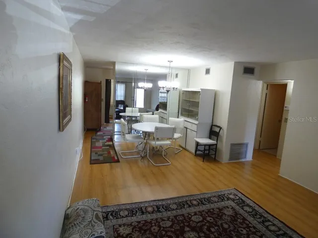 a living room with stainless steel appliances furniture a rug and a view of kitchen