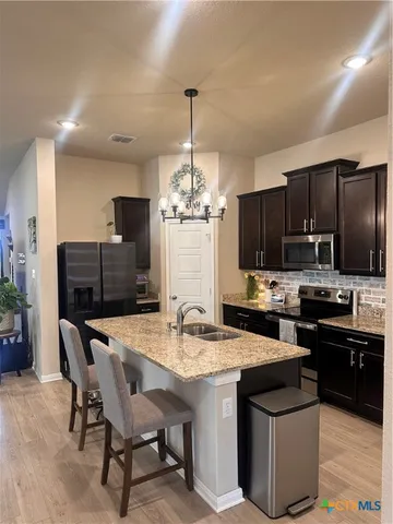 a kitchen with stainless steel appliances kitchen island granite countertop a sink dishwasher a stove a refrigerator with a dining table and chairs