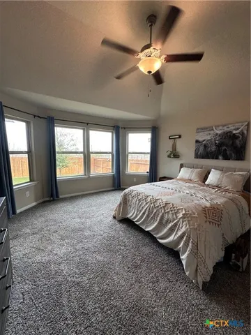 a spacious bedroom with a large bed and a chandelier fan