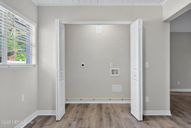 a view of an empty room with wooden floor and a window