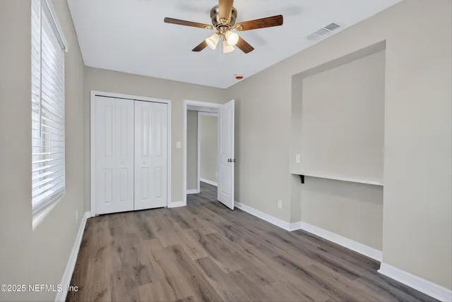 a view of empty room with wooden floor and fan