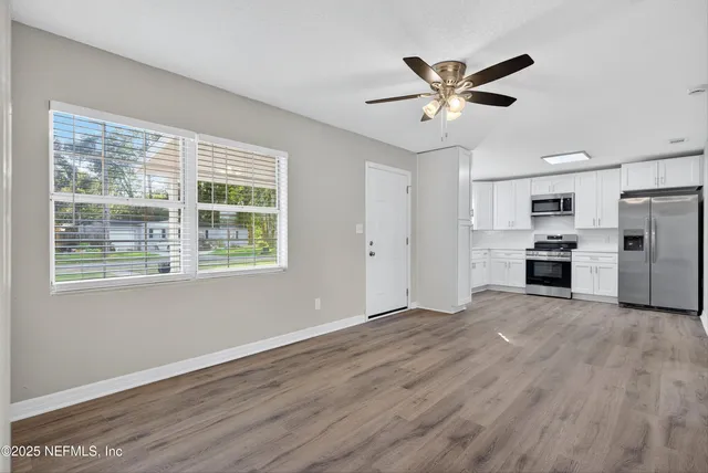 a view of a kitchen with wooden floor and a ceiling fan