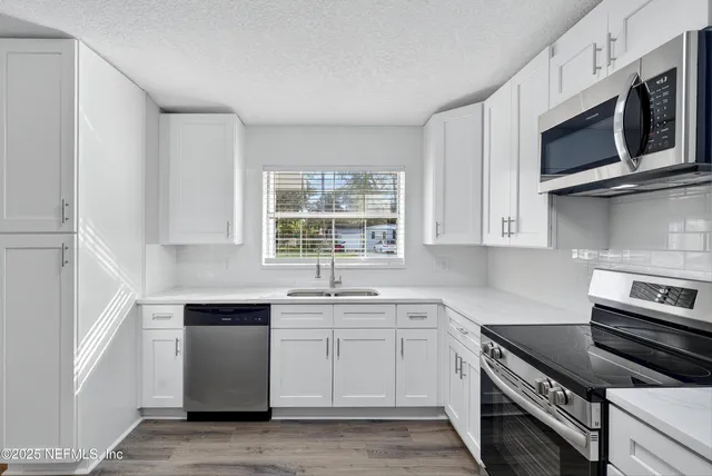 a kitchen with stainless steel appliances white cabinets and a sink