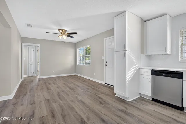 a view of an empty room with a kitchen and wooden floor