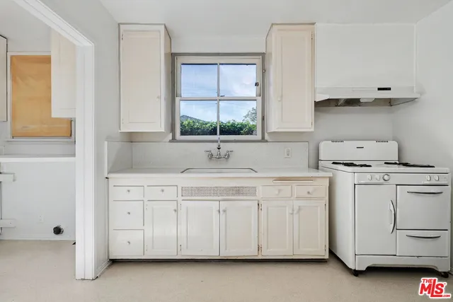 a kitchen with white cabinets and sink