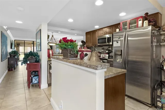 a kitchen with stainless steel appliances kitchen island granite countertop a refrigerator and a sink