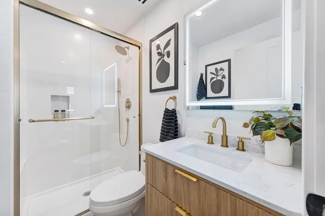 a bathroom with a granite countertop sink mirror vanity and toilet