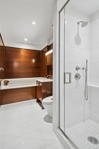 a bathroom with a double vanity sink a toilet and shower