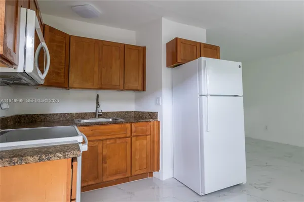 a kitchen with granite countertop a refrigerator a stove a sink and dishwasher