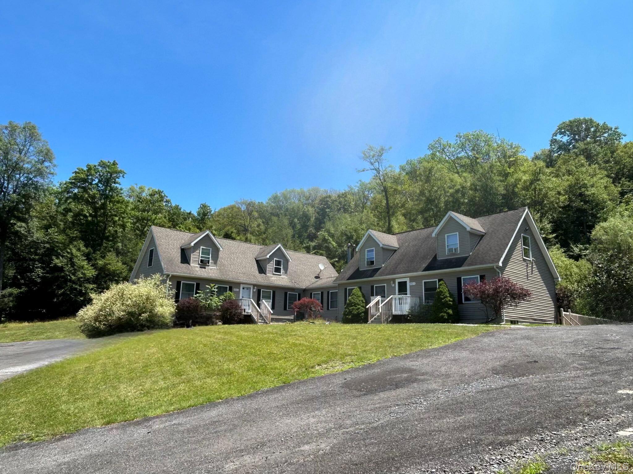 a front view of a house with a yard and large trees