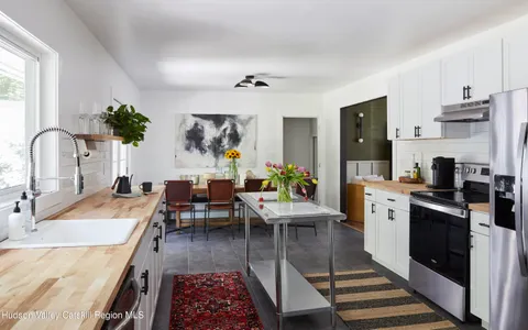 a living room with stainless steel appliances furniture a rug and a kitchen
