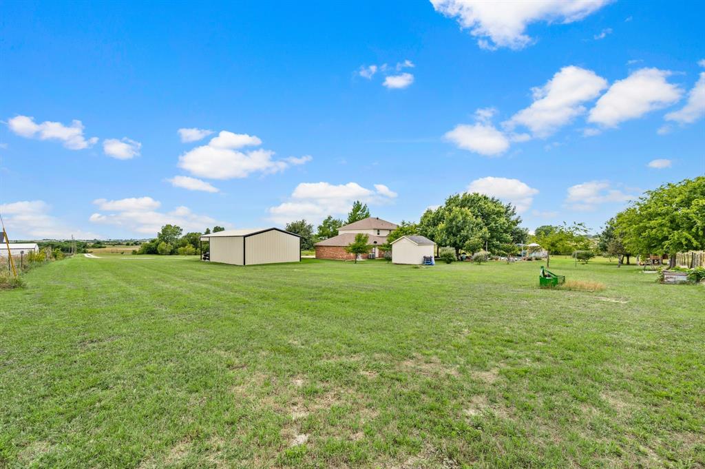 2141 Old Denton Road Decatur, TX 76234 - Photo 35 of 40 Expansive green lawn with a large metal outbuilding, a smaller storage shed, and mature trees