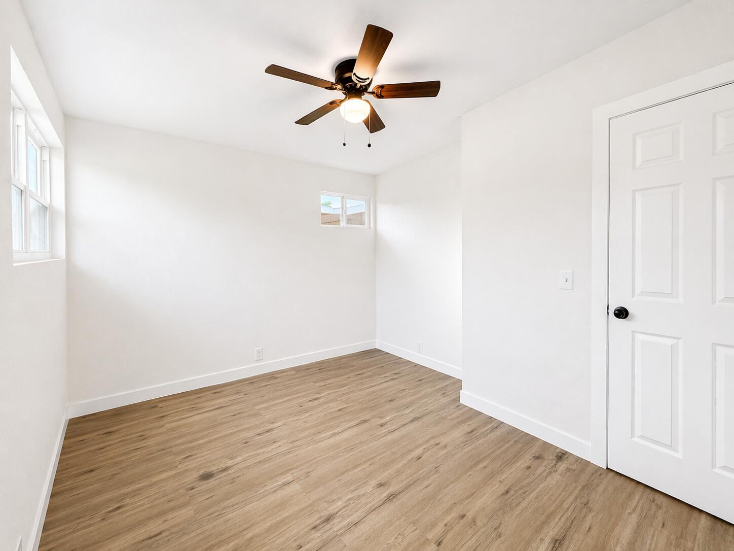 2316 48th Street Lubbock, TX 79412 - Photo 8 of 18 an empty room with wooden floor ceiling fan and windows