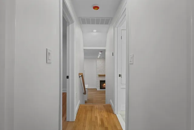 a view of a hallway with wooden floor and a bathroom