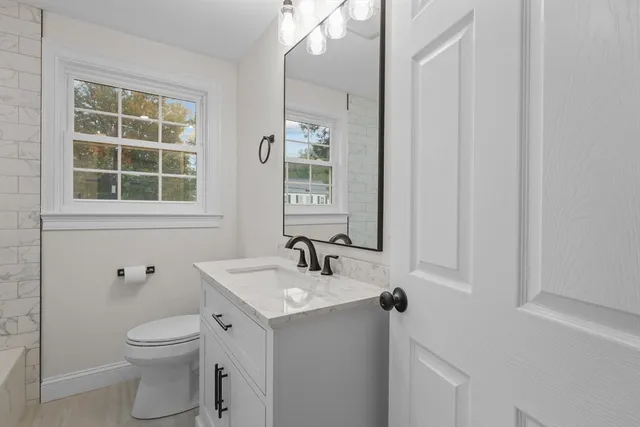 a bathroom with a toilet a sink a mirror and shower