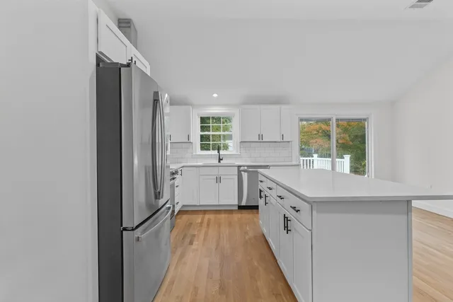a kitchen with white cabinets appliances and a window