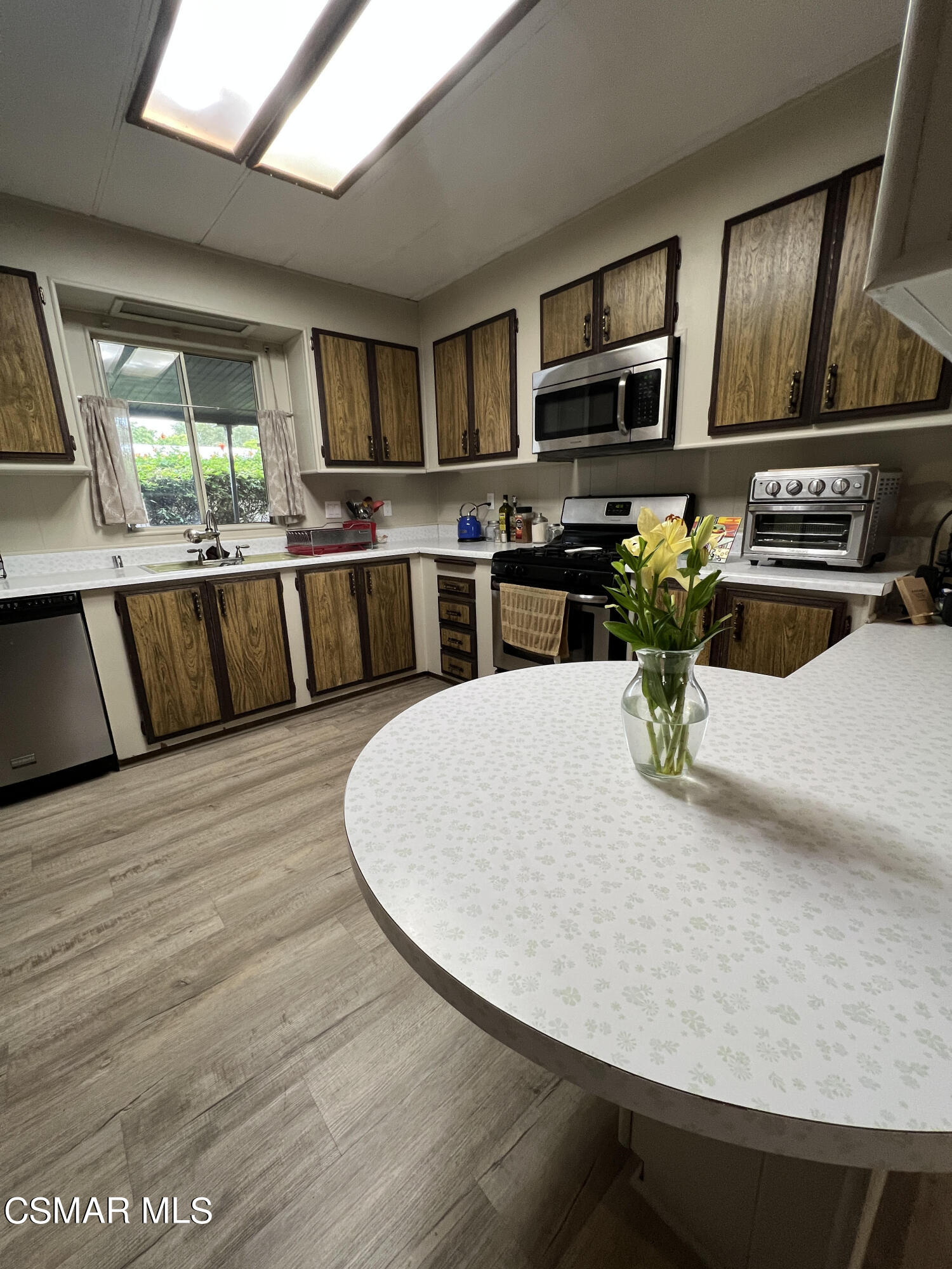 1550 Rory Lane, Unit 83 Simi Valley, CA 93063 - Photo 17 of 50 a kitchen with stainless steel appliances kitchen island granite countertop a refrigerator a stove and a sink with wooden floor