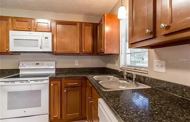 a kitchen with granite countertop a sink stove and cabinets