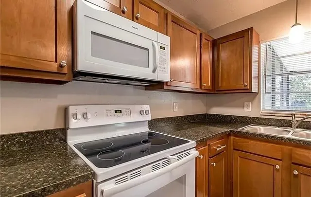 a kitchen with granite countertop cabinets stainless steel appliances and a sink
