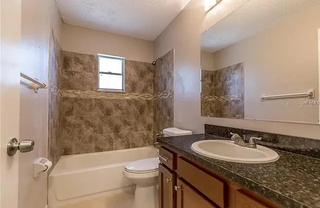 a bathroom with a granite countertop sink toilet and shower