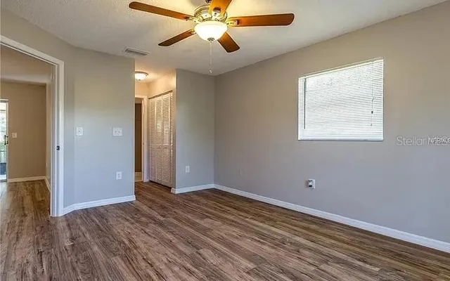 a view of an empty room with wooden floor and a window
