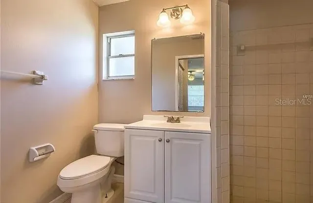 a bathroom with a granite countertop toilet a sink and mirror