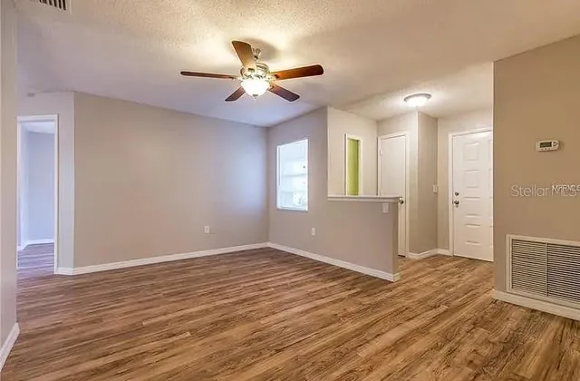 a view of an empty room with wooden floor and a window