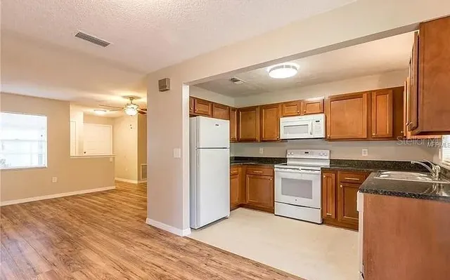 a kitchen with granite countertop a refrigerator stove top oven and sink