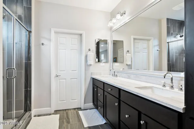 a bathroom with a double vanity sink a mirror and a shower