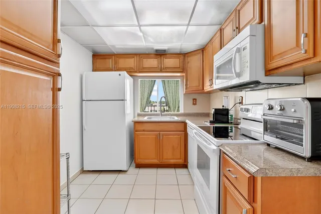 a kitchen with a refrigerator a stove top oven a sink and cabinets